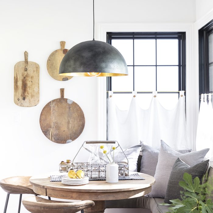 Breakfast nook with a black ceiling light, a wooden table, and white drapes