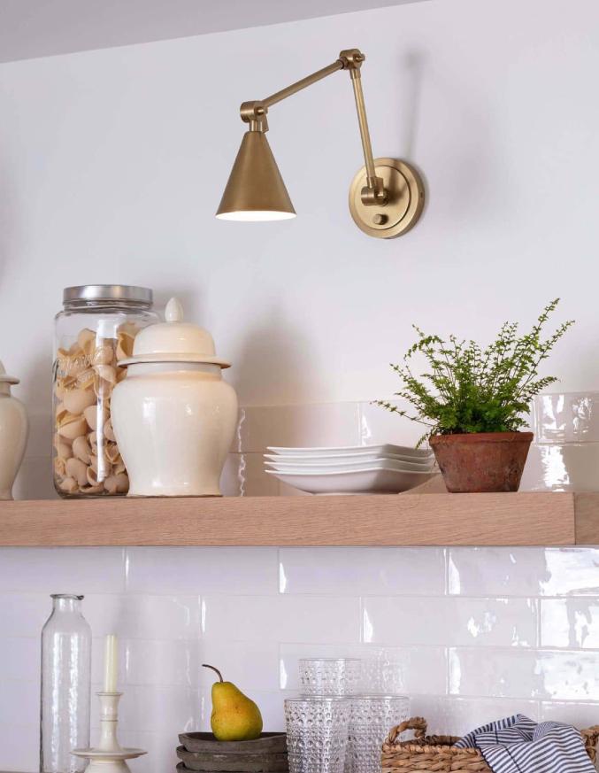 natural brass wall sconce above kitchen shelf with dishes