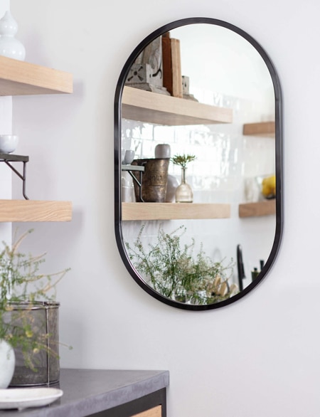 Living room with a nook and a bold black curved mirror