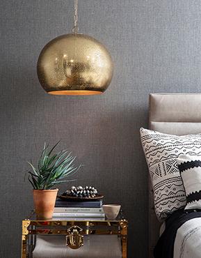 So-Cal style bedroom with an antique trunk side table, and a pierced metal pendant finished in natural brass