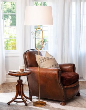 Living room leather chair with a wooden table and a tall natural brass french deco lamp with two glass butterflys