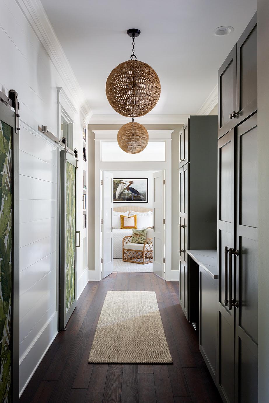 Green hallway with a small runner rug and two modern coastal styled pendant