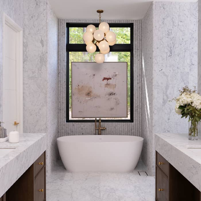 bathroom with a white tub, a chandelier with multiple clear glass bulbs