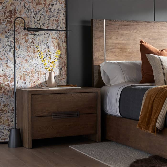 White bed with gray side table with a gray lamp on top