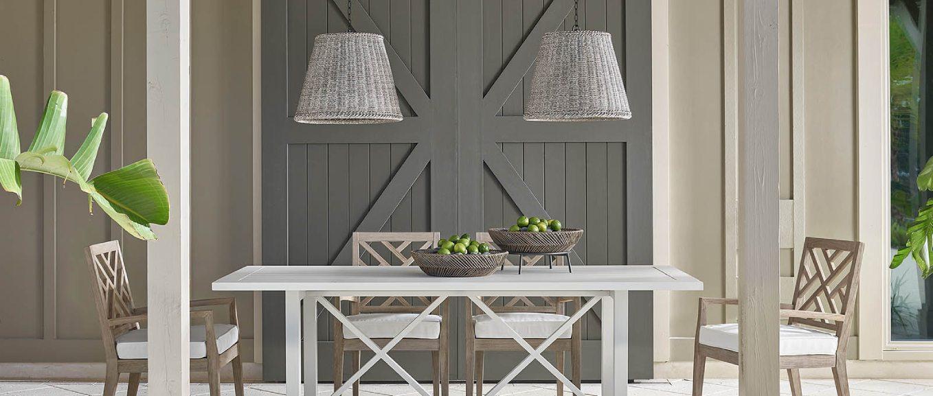 Outdoor patio with gray chairs and table, and two gray wicker pendants