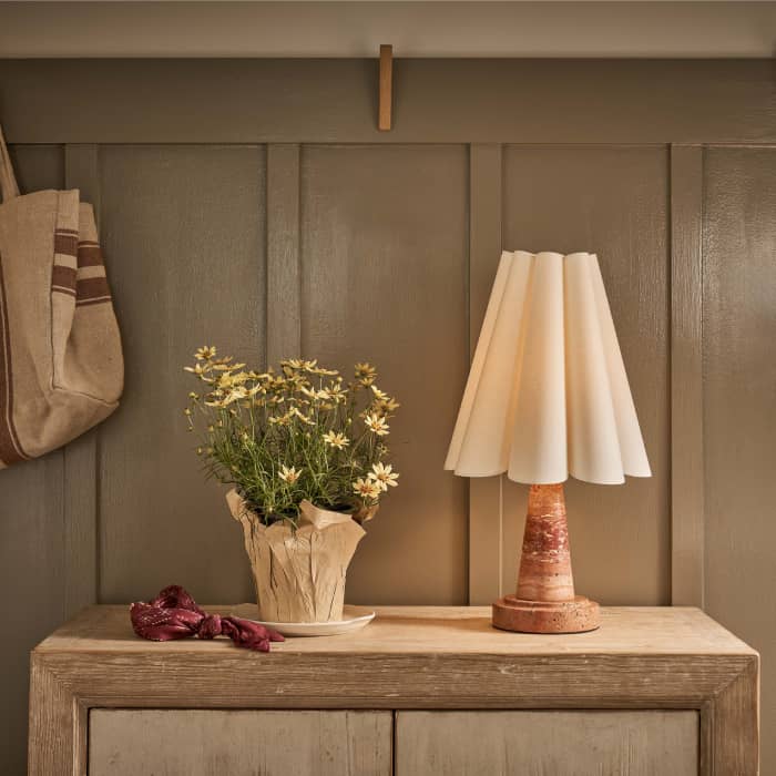 Entryway console with a bowl of greenery and two white and gold pendants