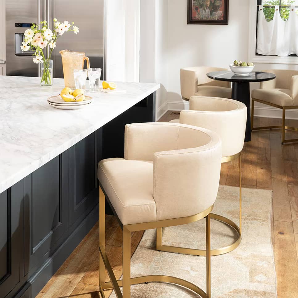 Kitchen with a black waterfall countertop, white chairs and white ceiling pendants