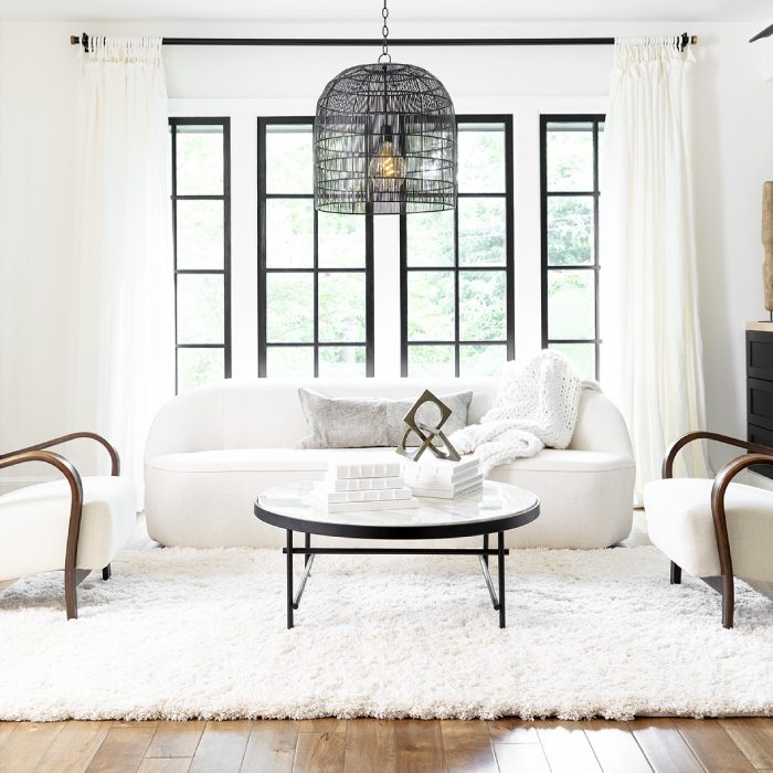 Living room with a white wool carpet, black glass coffee table, white chairs, and a white couch