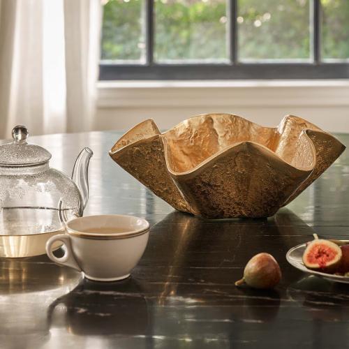 Metal scalloped bowl beside kettle of tea