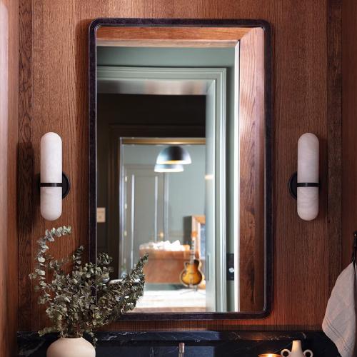 Black leather mirror beside two sconces
