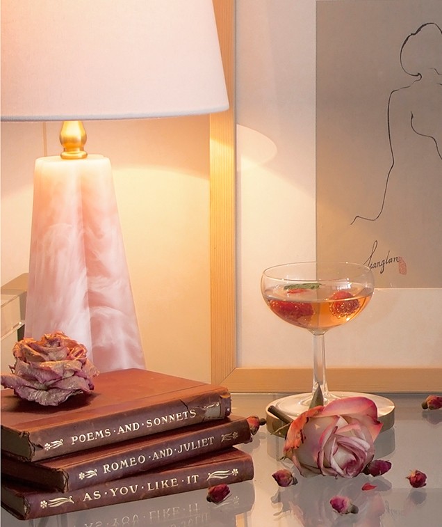 Glass tabletop with dried flowers, red books, and a pink crystal table lamp