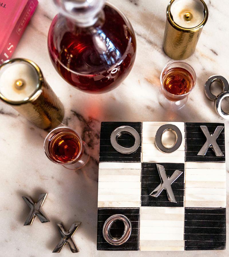 Marble countertop with bone black and white tic tac toe set and two hammered candle holders