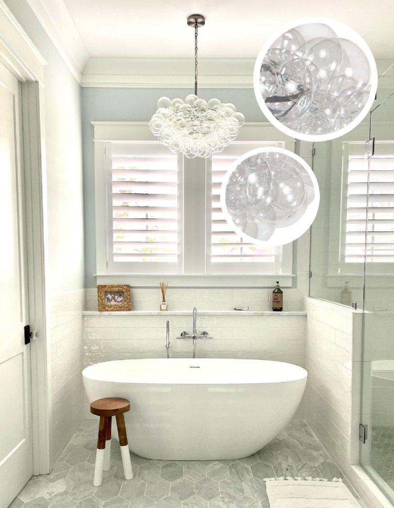 Bathroom with white shutters, a glass bubl chandelier, and bathtub