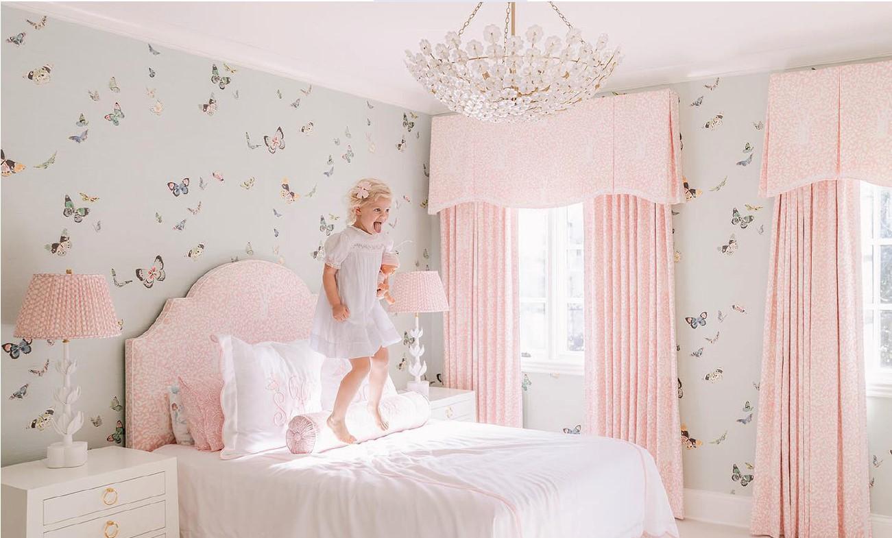 Young girl jumping on a bed in a pink bedroom with butterflys on the walls