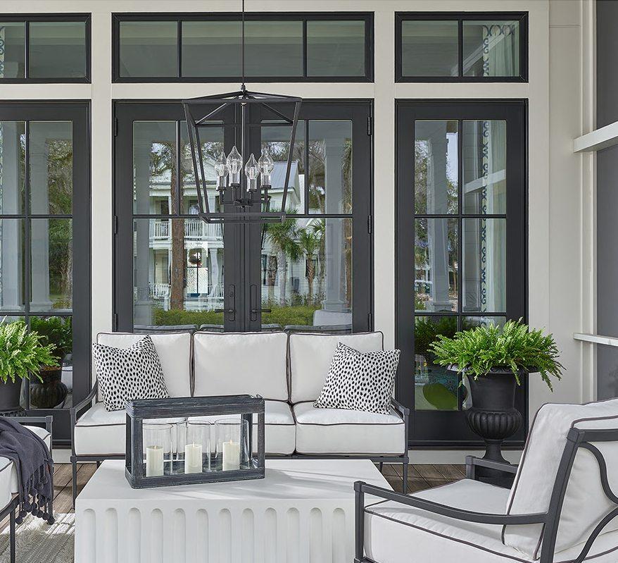 Covered porch with gray sofas and chairs, a concrete coffee table, and a black chandelier