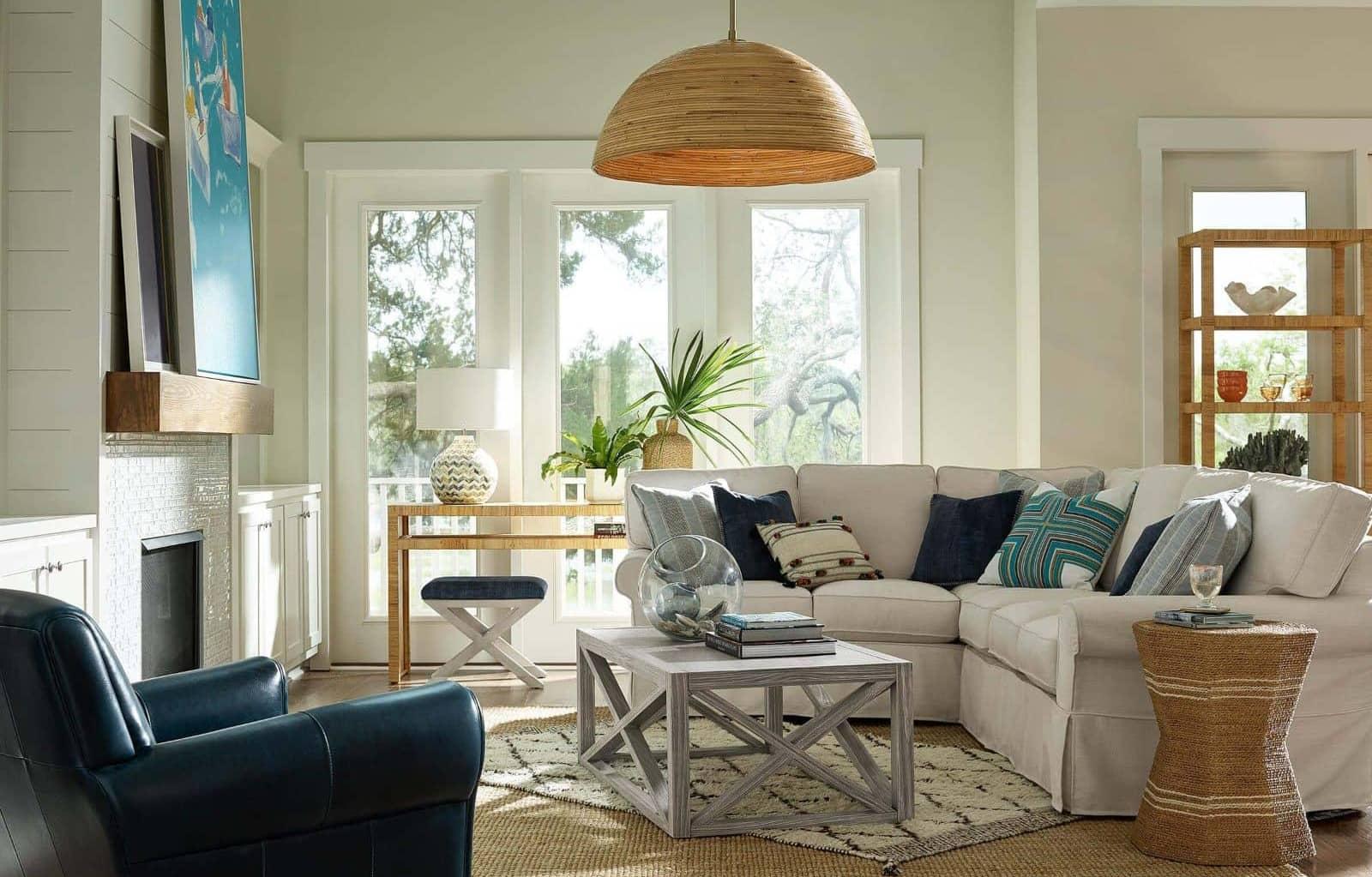 A coastal styled living room with a white couch, blue leather chair, and rattan side table