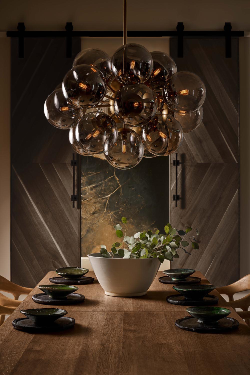Smoke and glass chandelier above a wood dining table
