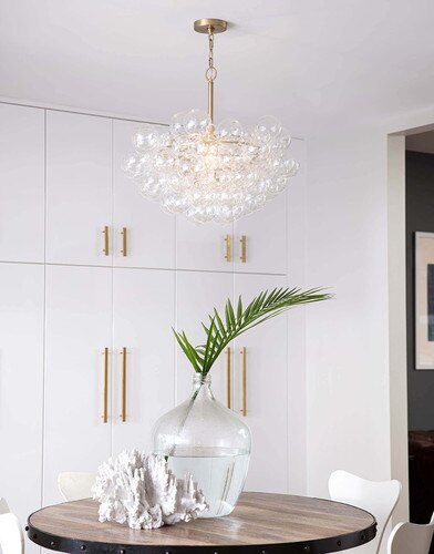 Whimsical dining room with a large coral sculpture, a large glass vase with a leaf, and a glass chandelier with multiple sized glass globes