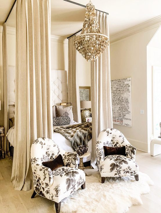 Glamorous bedroom with tall ceilings, a faux fur rug, and a costal style abalone shell chandelier with a silver-gold frame