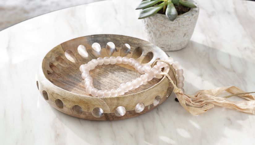 Wooden dish with a bracelet in it on a marble countertop