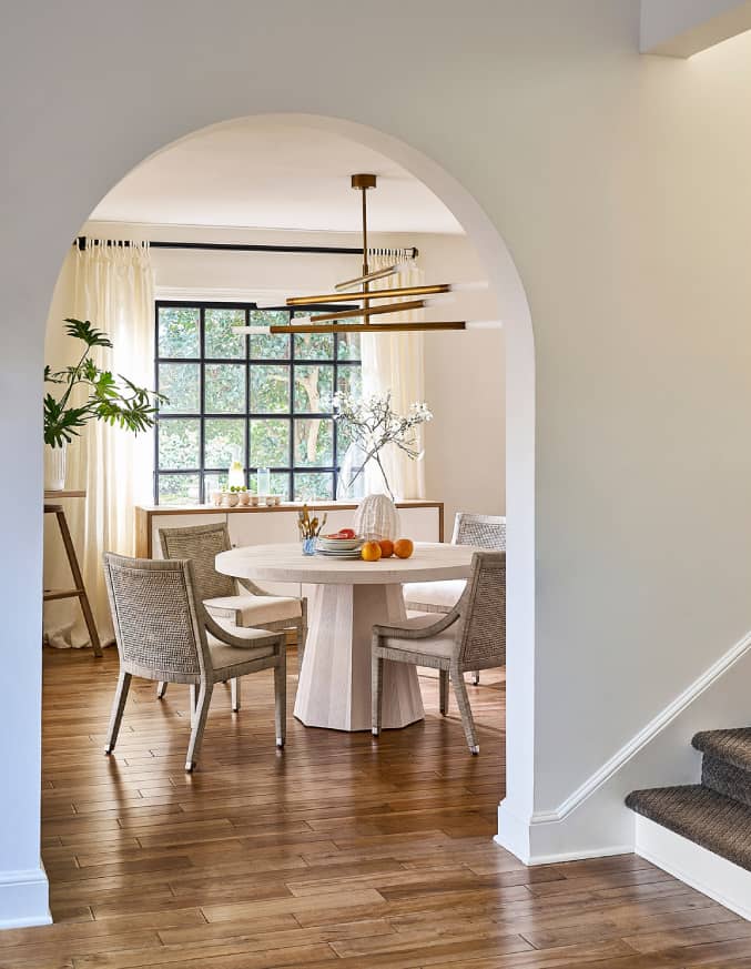 grey round dining room table with a brass chandelier above it