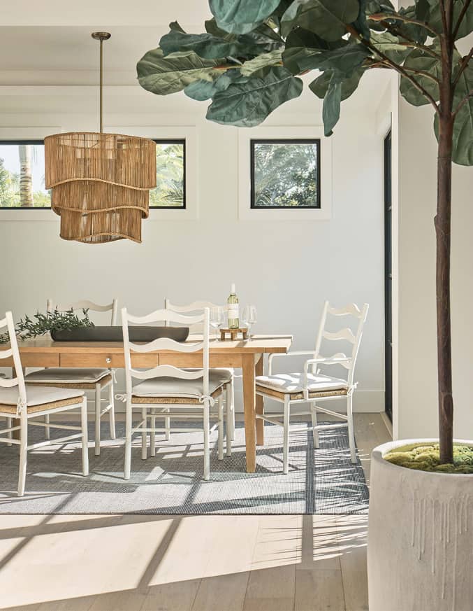 A wood dining table with white and wicker chairs around it