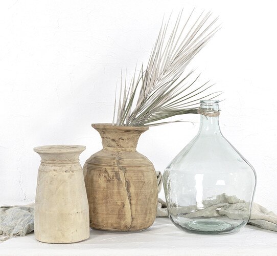 Two water pots with florals in them next to a glass vase