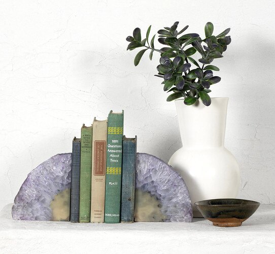 Geode bookends supporting vintage books next to a ceramic bowl and vase