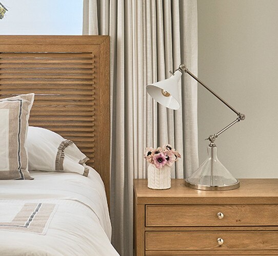 Glass and polished nickel task lamp on wooden bedside table