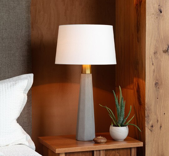 Concrete table lamp with brass finial on a wooden nightstand