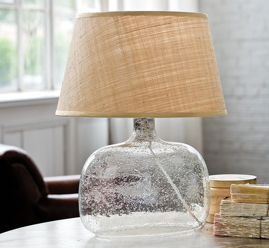 textured glass lamp with a rattan shade on a wooden side table