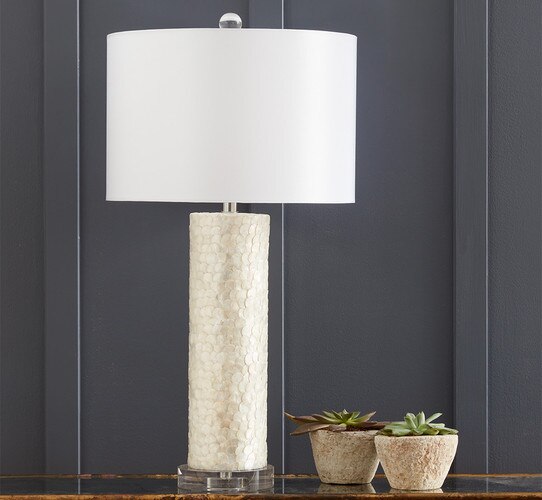 Scalloped white table lamp on a wood table next to two succulents