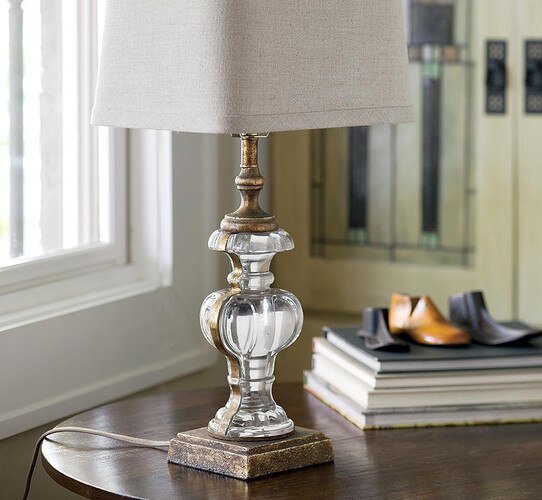 Glass and patinaed metal table lamp on a wooden side table