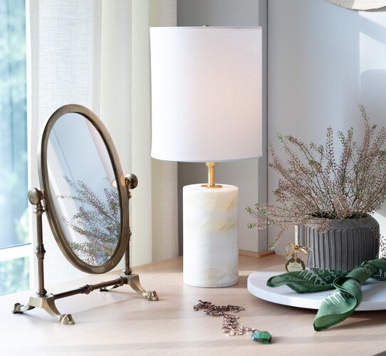 Brass and jade mini lamp on a desk next to a small mirror