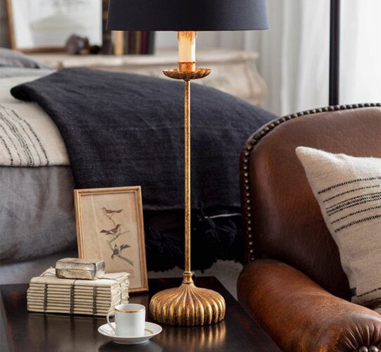 Gold leaf lamp on a side table with books and a cup of espresso