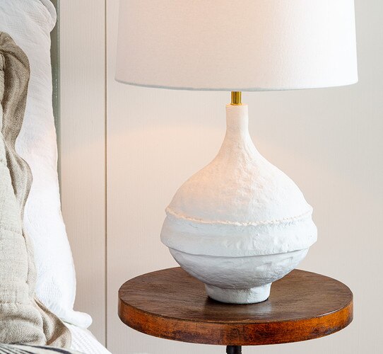 White textured table lamp with a wide base on a wooden side table