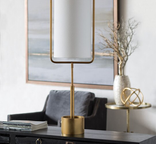 Modern brass lamp with an enclosed shade on a wooden console table
