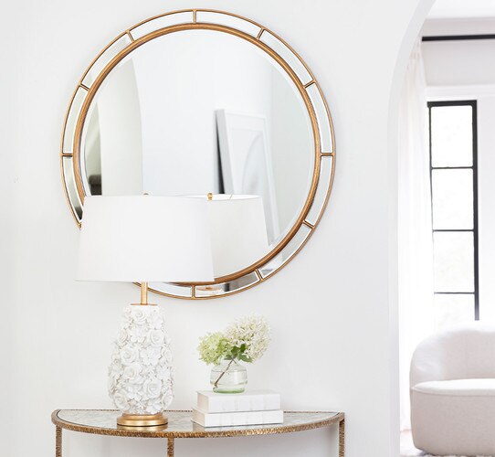 White flower lamp with gold base on a console table under a mirror