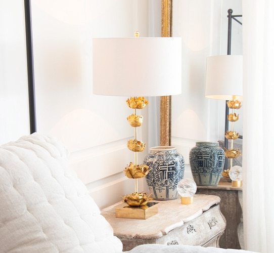 Gold table lamp with flowers interspersed in the center on a wooden nightstand