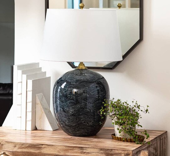 Navy blue ceramic lamp on a wicker side table next to a white couch