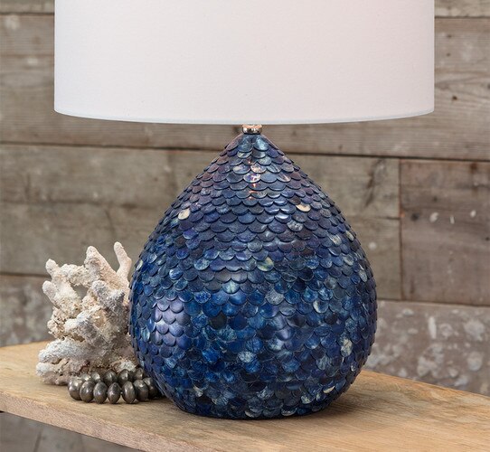 Blue table lamp with multi-colored scales next to a decorative piece of coral