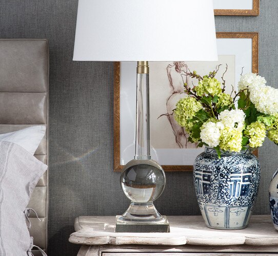Tall crystal table lamp on a wooden bedside table