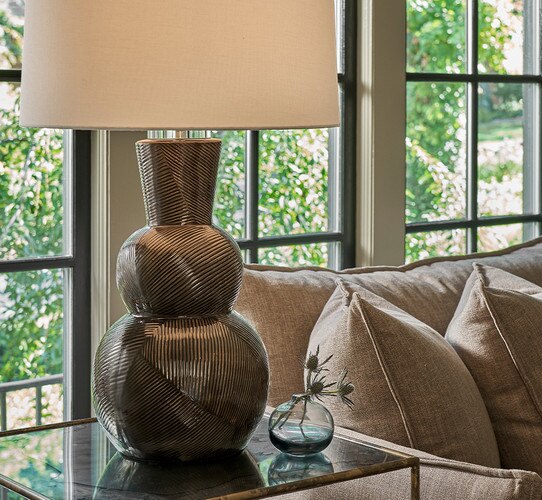 Black textured three-tiered table lamp on a side table next to a brown couch