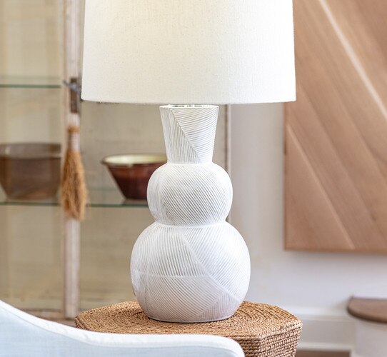 White textured three tiered table lamp on a wicker side table