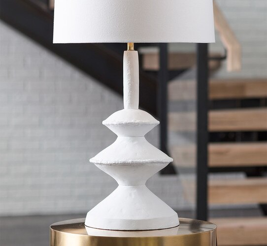 Organically shaped white table lamp on a brass side table