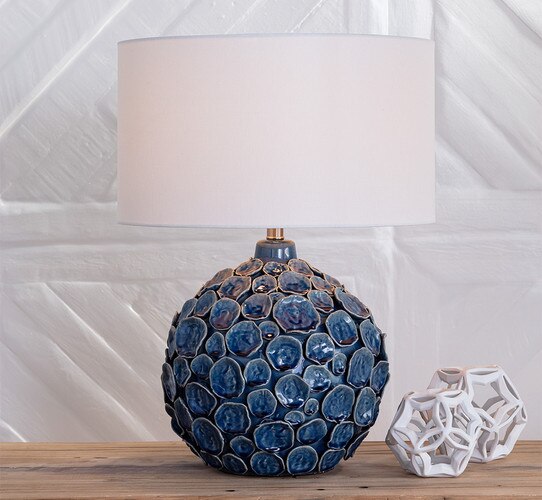 Hand crafted lamp with multi-sized discs next to two white geometric sculptures