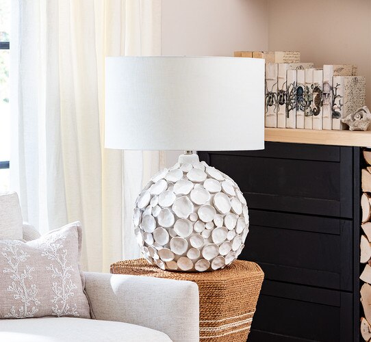 Hand crafted white lamp with hand shaped disks on a rattan side table
