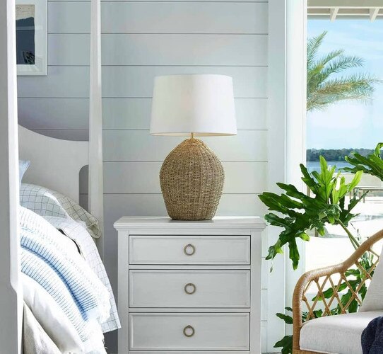White rattan lamp next to two clear glass vases