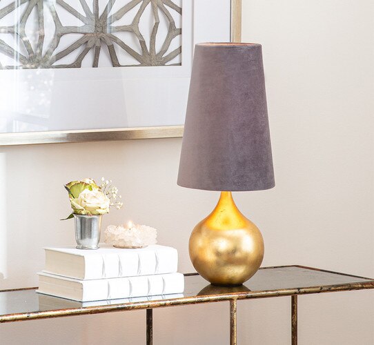 Gold small table lamp with a velvet shade on a golden side table