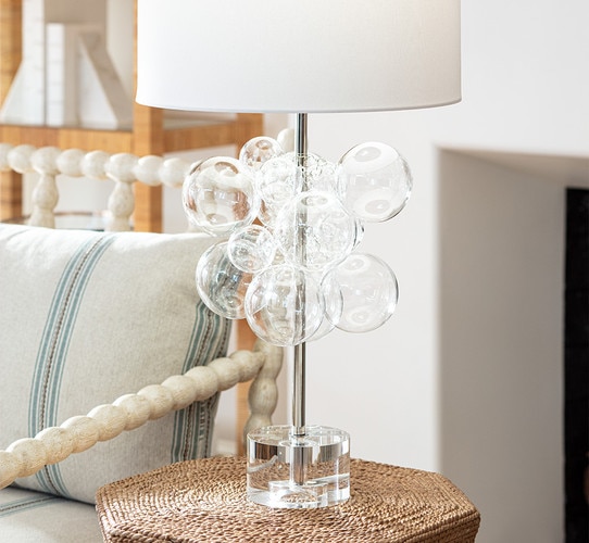 Glass bubble table lamp on a wicker side table